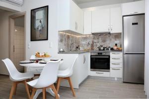 a kitchen with white cabinets and a table and chairs at Under the Aqueduct boutique house in Kavála