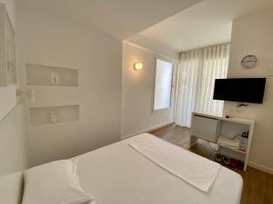 a white bedroom with a bed and a flat screen tv at Aleksi rooms in Shëngjin
