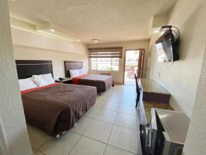 um quarto de hotel com duas camas e uma televisão de ecrã plano em Motel Reno em Tijuana