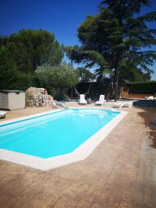a swimming pool with two chairs and a tree at Madrid Green in Villaviciosa de Odón