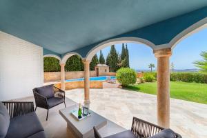 een overdekte patio met een tafel en stoelen en een zwembad bij Villa Mimosa sleeps 8 with Heated Pool in Santa Fe de los Boliches