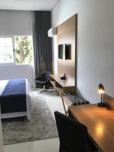 una habitación de hotel con una cama y un escritorio en Flat Itaipava - Granja Brasil, en Itaipava