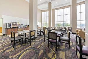 uma sala de jantar com mesas, cadeiras e janelas em La Quinta by Wyndham Bridge City em Bridge City