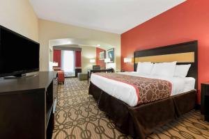 Una habitación de hotel con una cama grande y un televisor de pantalla plana. en La Quinta by Wyndham Leesville Ft. Polk, en Leesville