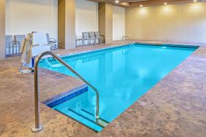 a large swimming pool in a hotel room with chairs at La Quinta by Wyndham Guthrie in Guthrie