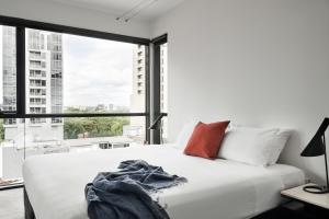 - une chambre avec un lit blanc et une grande fenêtre dans l'établissement Punthill Apartment Hotel - Manhattan, à Melbourne