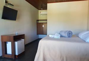 a bedroom with a bed and a tv on the wall at Marinas Pousada in Pasto da Mata