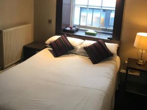 a white bed with two pillows and a window at Rab Ha's in Glasgow