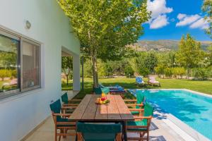 Villa Verano - Private Heated Pool في Lagópodhon: فناء مع طاولة وكراسي خشبية بجوار حمام سباحة