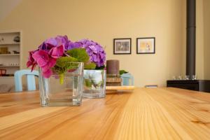 two vases with purple flowers on a wooden table at Casa da Quinta in Vila Franca do Campo