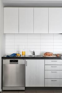 a kitchen with white cabinets and a dishwasher at Punthill Essendon in Melbourne