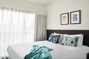 a bedroom with a white bedspread and pillows at Punthill Essendon in Melbourne