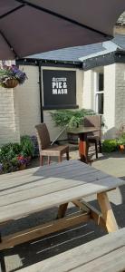 a picnic table and two chairs and a table and a sign at The Swan Hotel in Eynsham