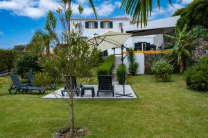 a garden with chairs and an umbrella in front of a house at Casa da Quinta in Vila Franca do Campo