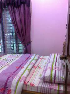 1 cama en un dormitorio con cortina púrpura en RumahTamu SURURINA, en Kota Bharu