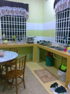 cocina con mesa, mesa y fregadero en RumahTamu SURURINA, en Kota Bharu