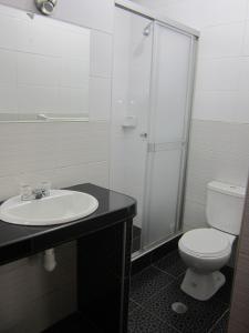 a bathroom with a toilet and a sink and a shower at Hotel Plaza Trujillo in Trujillo