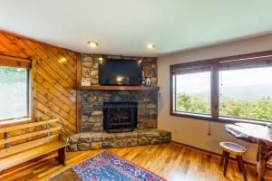 a living room with a stone fireplace and a tv at Crest 100E in Sugar Mountain