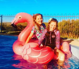 two young girls are sitting on an inflatablevisor in the water at Surfpoint Resort in Margaret River Town