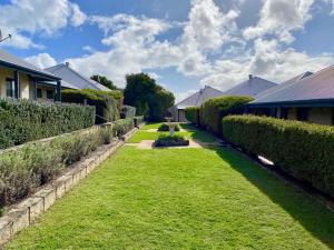 a yard with hedges and a building and a house at Surfpoint Resort in Margaret River Town