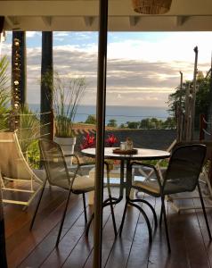 a table and chairs on a patio with a view of the ocean at Indigo Palmes in Sainte-Rose