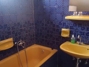 ein blau gefliestes Bad mit einer Badewanne und einem Waschbecken in der Unterkunft Cola Panzió in Szentendre