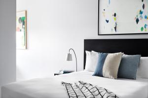 a bed with white sheets and blue pillows at Punthill Ivanhoe in Melbourne