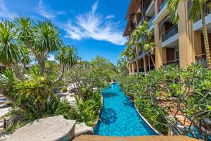 einem Resortkorridor mit einer blauen Wasserstraße vor einem Gebäude in der Unterkunft Rawai Palm Beach Resort - SHA Extra Plus in Rawai Beach