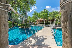 a swing bridge over a swimming pool at a resort at Rawai Palm Beach Resort - SHA Extra Plus in Rawai Beach