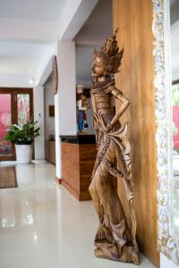 een houten beeld van een vrouw die tegen een muur leunt bij CASA MIMBA - Seaview Private Pool Villa Padangbai in Padangbai