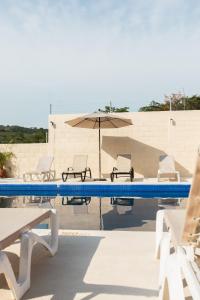 a swimming pool with chairs and an umbrella at hotel isla Bonita in Zihuatanejo