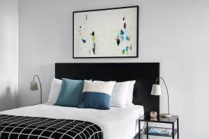 a bedroom with a bed with white sheets and blue pillows at Punthill Ivanhoe in Melbourne