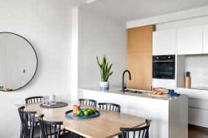 a kitchen with a table, chairs, and a refrigerator at Punthill Ivanhoe in Melbourne