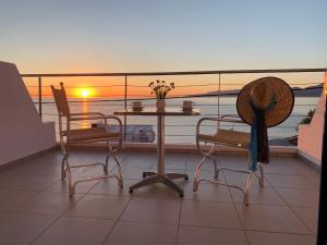 een tafel en stoelen op een balkon met uitzicht op de oceaan bij Kassavetis Center - Hotel Studios & Apartments in Chersonissos