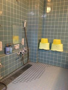 baño de azulejos azules con ducha y 2 aseos amarillos en Fujiyoshi, en Nozawa Onsen