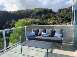 a couch on a balcony with a view of the mountains at Love Akaroa Retreat in Akaroa