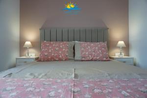 una camera da letto con un grande letto con cuscini rosa di Casa Vista Fall a Karpathos