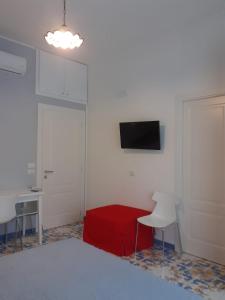 1 dormitorio con cama roja, mesa y TV en Casa Vacanze Baia Garagliano, en Scario