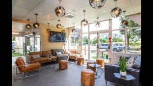 a lobby with couches and tables and windows at Ibis Styles Bobigny Centre Préfecture in Bobigny