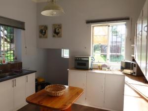 a kitchen with white cabinets and a wooden table at Linduli Farmstay in Cradock