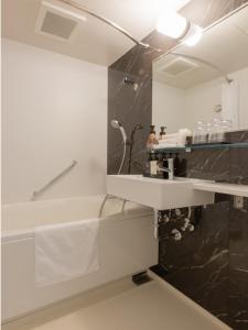 La salle de bains est pourvue d'un lavabo et d'un miroir. dans l'établissement Tosei Hotel Cocone Asakusa Kuramae, à Tokyo