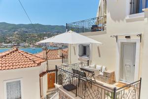 - un bâtiment blanc avec un parasol sur le balcon dans l'établissement Euphoria House, à Poros