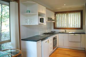 a kitchen with white cabinets and a sink and a microwave at Bewong River Retreat in Bewong