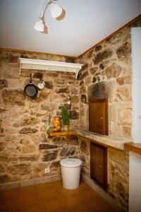 una cucina con pareti in pietra, lavandino e servizi igienici di Miña Nai, Casa Rural a Lalín