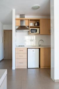 a kitchen with a refrigerator, microwave, sink and dishwasher at Apartamentos Vistamar II in Playa d'en Bossa