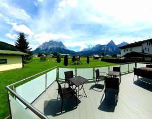 a deck with chairs and tables and a view of mountains at B&B Gästehaus Alpenblick in Lermoos