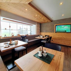 ein Restaurant mit Tischen und Stühlen und einem Flachbild-TV in der Unterkunft B&B Gästehaus Alpenblick in Lermoos
