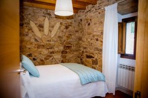 a bedroom with a bed with a stone wall at Miña Nai, Casa Rural in Lalín +44 photos