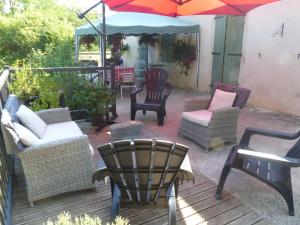 un patio con sillas, mesas y una sombrilla en CHEZ d'eau en Marigny-le-Cahouet