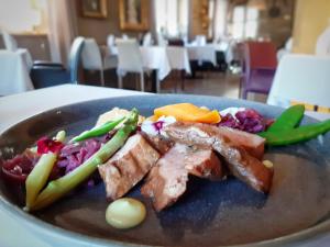 een bord met vlees en groenten op tafel bij Hotel La Couronne in Ensisheim